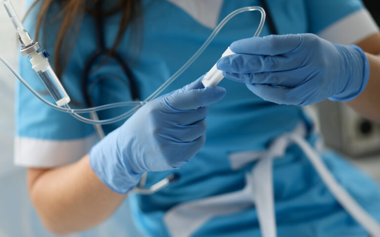 Female nurse hand in blue protective gloves hold dropper